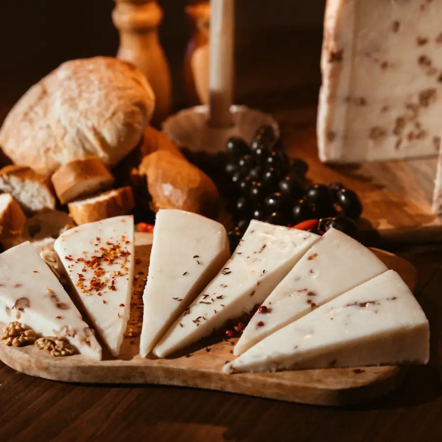 Punten truffelkaas met zwarte truffelstukjes op een plank bij kaarslicht